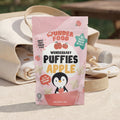 Wunderbaby Puffies Apple packaging on a wooden surface with a picnic setup in the background